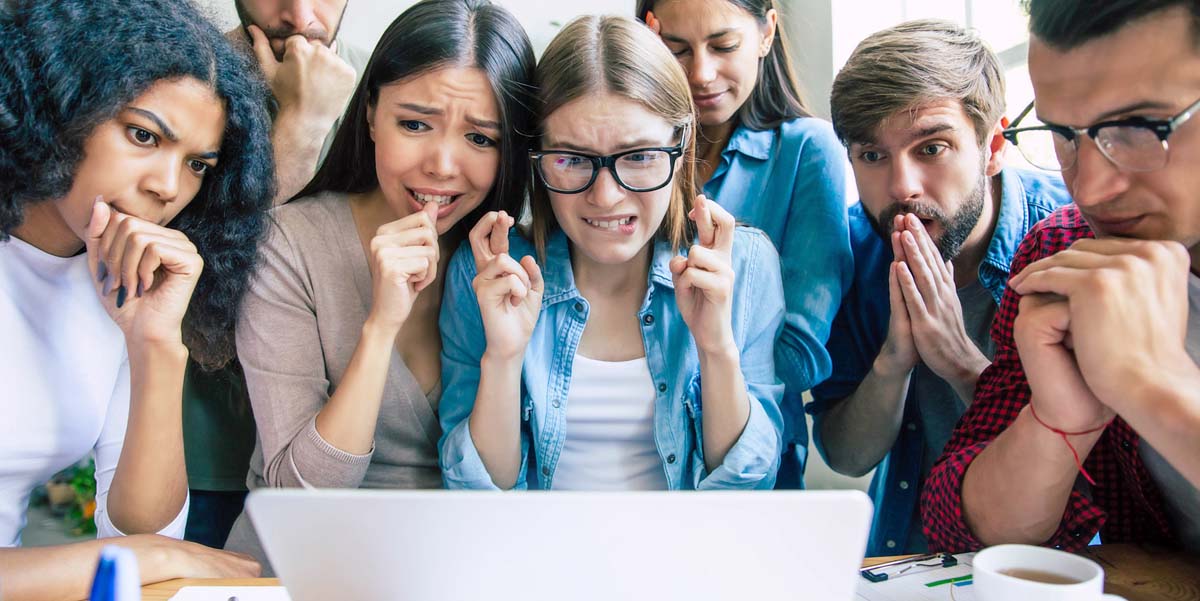 image: Several young men and women gather around a laptop computer with nervous excitement to view the results of their crowdsource campaign