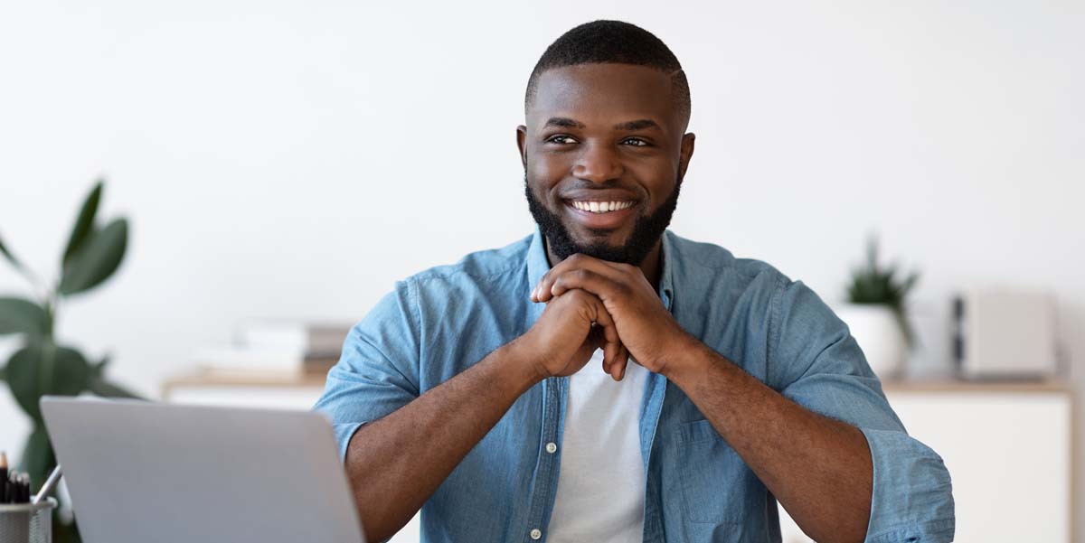 Casually-dressed young professional sits at desk with calm and happy face