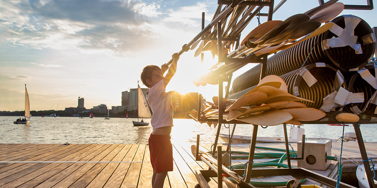 Young boy on a pier returning rowing oar.