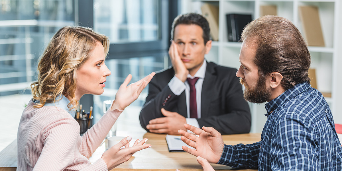 Two men and a woman sitting at a table engaged in an intense discussion.