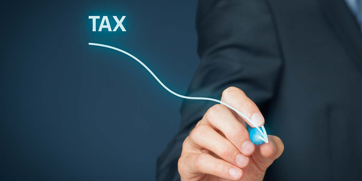 Male hand of man insuit draws a downward wavy arrow with the word tax at the top indicating lower taxes.