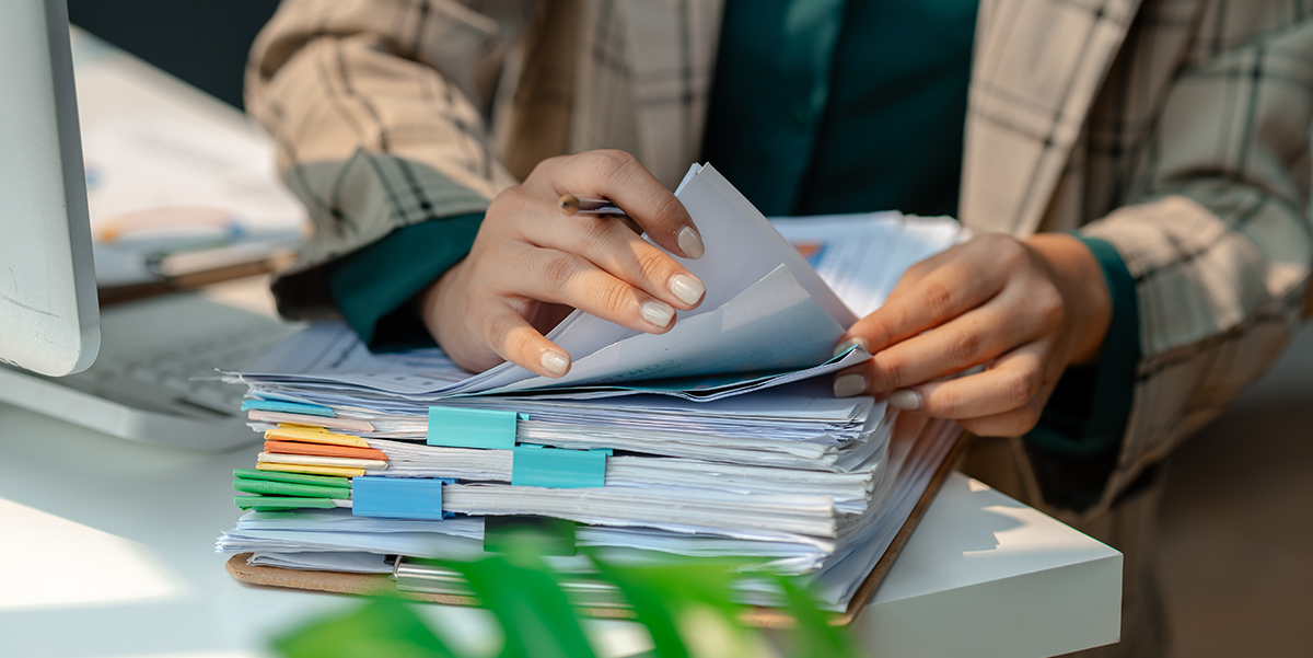 Closeup of person's hands sorting through a pile of documents.